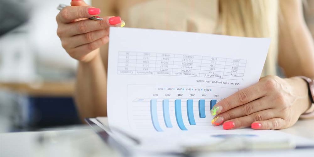 woman-s-hand-holds-pen-document-with-commercial-indicators-chart