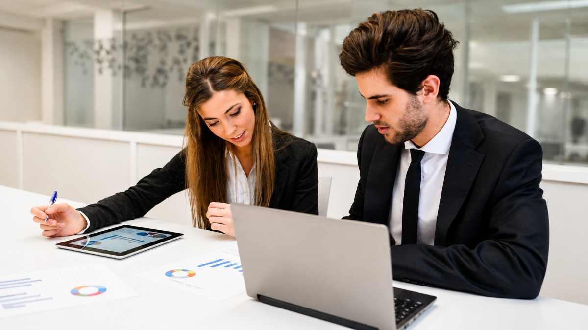 Two professionals reviewing reports and data on a laptop and tablet, representing the path to becoming a CQI IRCA Certified Auditor or Lead Auditor.